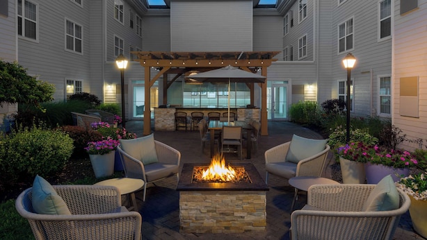 A patio area with a fire pit, outdoor furniture, and a pergola. - Homewood Suites by Hilton Buffalo Airport (Buffalo)