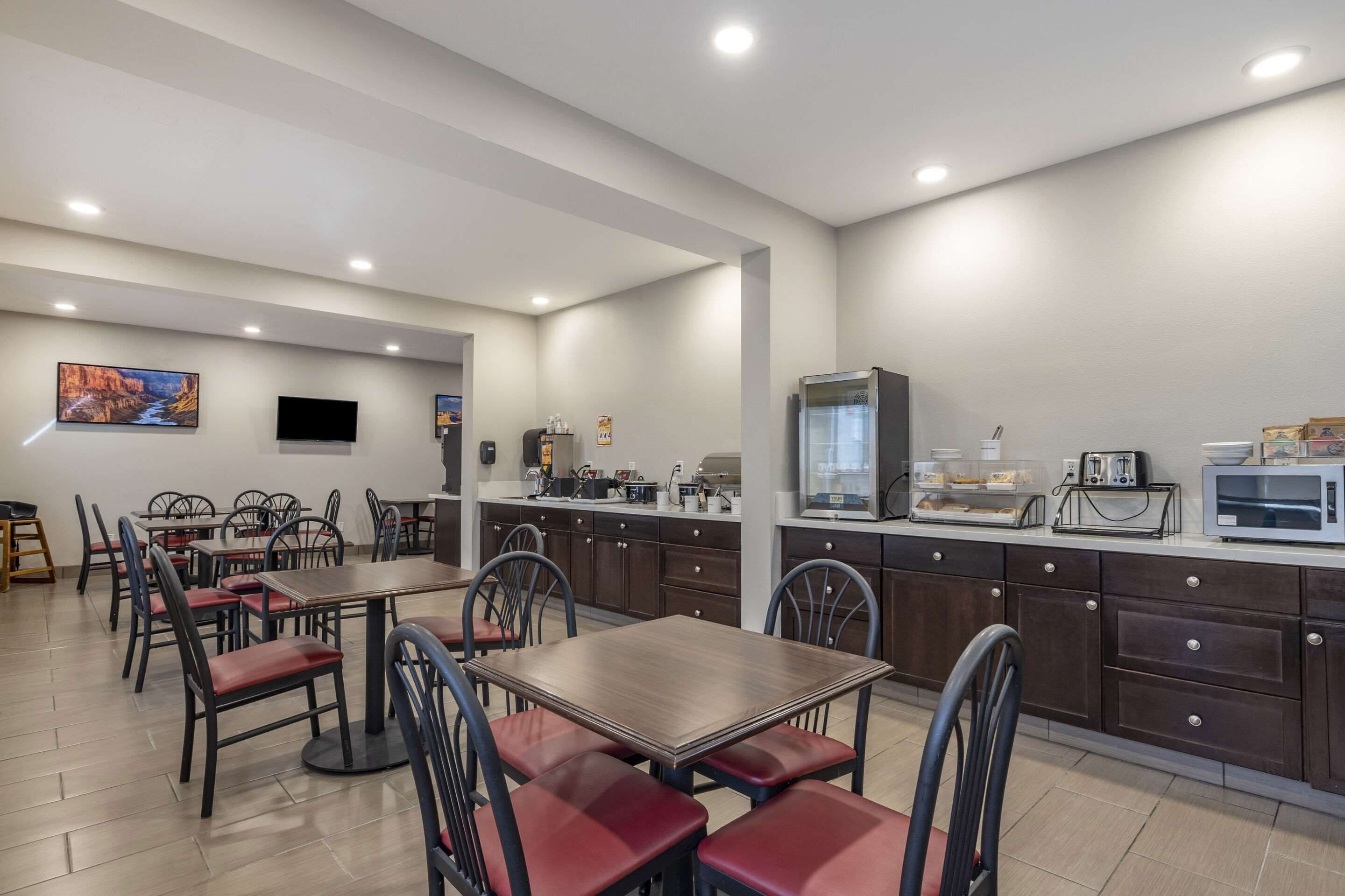 Un'area pranzo moderna con un lungo bancone, diverse opzioni di seduta e una zona cucina completa di elettrodomestici.