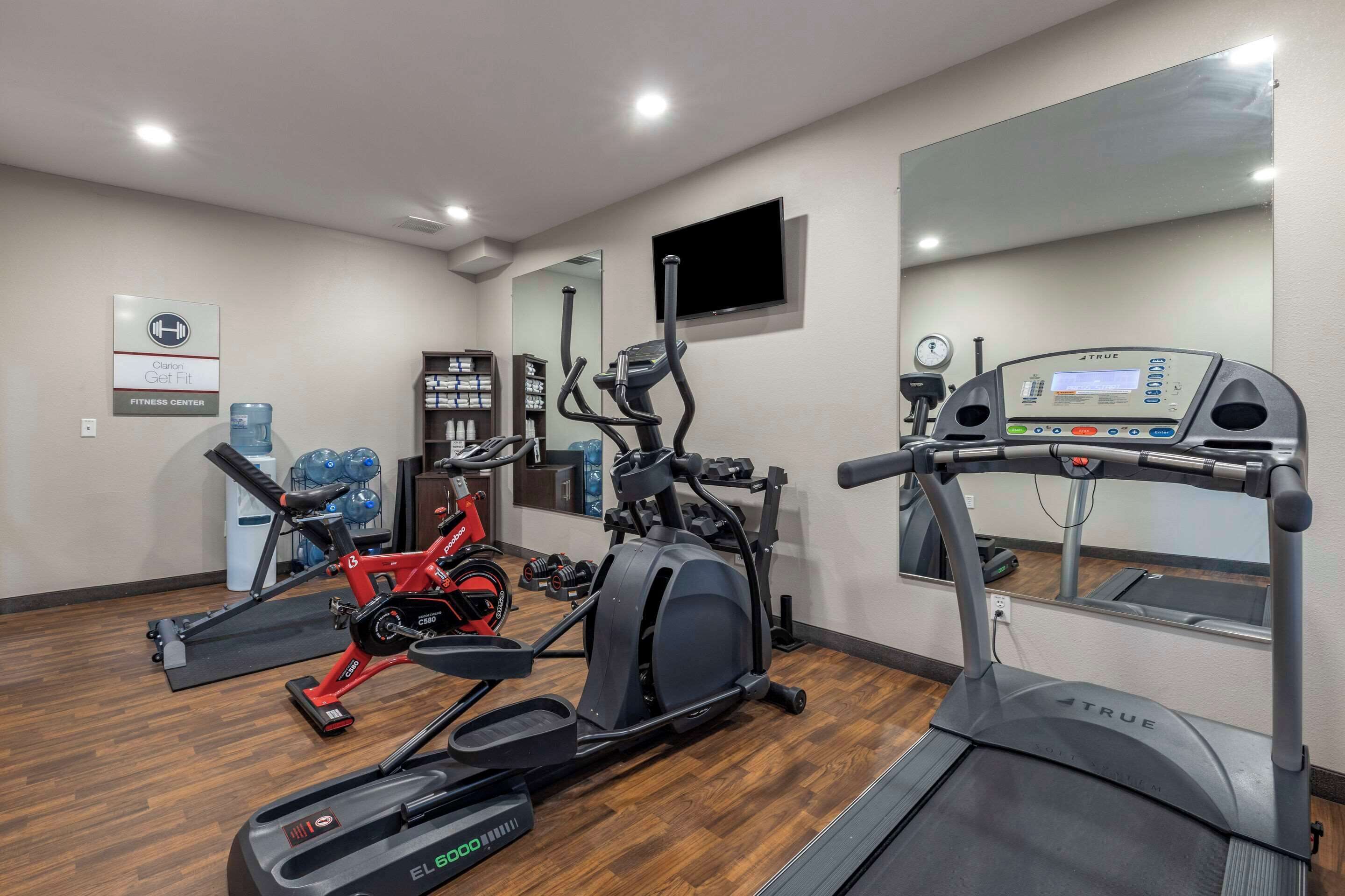 A fitness center with cardio machines, a treadmill, and a mirrored wall.