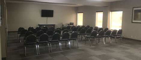 A conference room with rows of chairs, a flat-screen TV, and large windows.