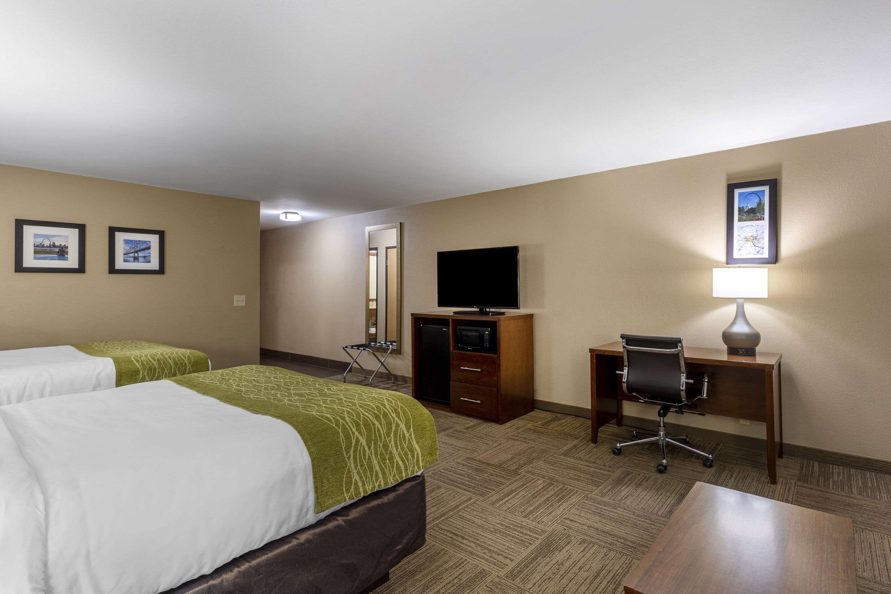 A hotel room with two beds, a desk with a chair, a television, and a desk lamp.