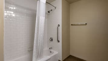A bathroom with a white bathtub, a shower with a curtain, and a grab bar.