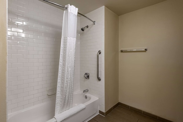 A bathroom with a white bathtub, a shower with a curtain, and a grab bar. - Comfort Inn Collinsville near St. Louis (Collinsville)