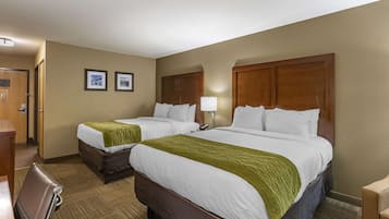 A hotel room with two beds, a desk, and a chair.