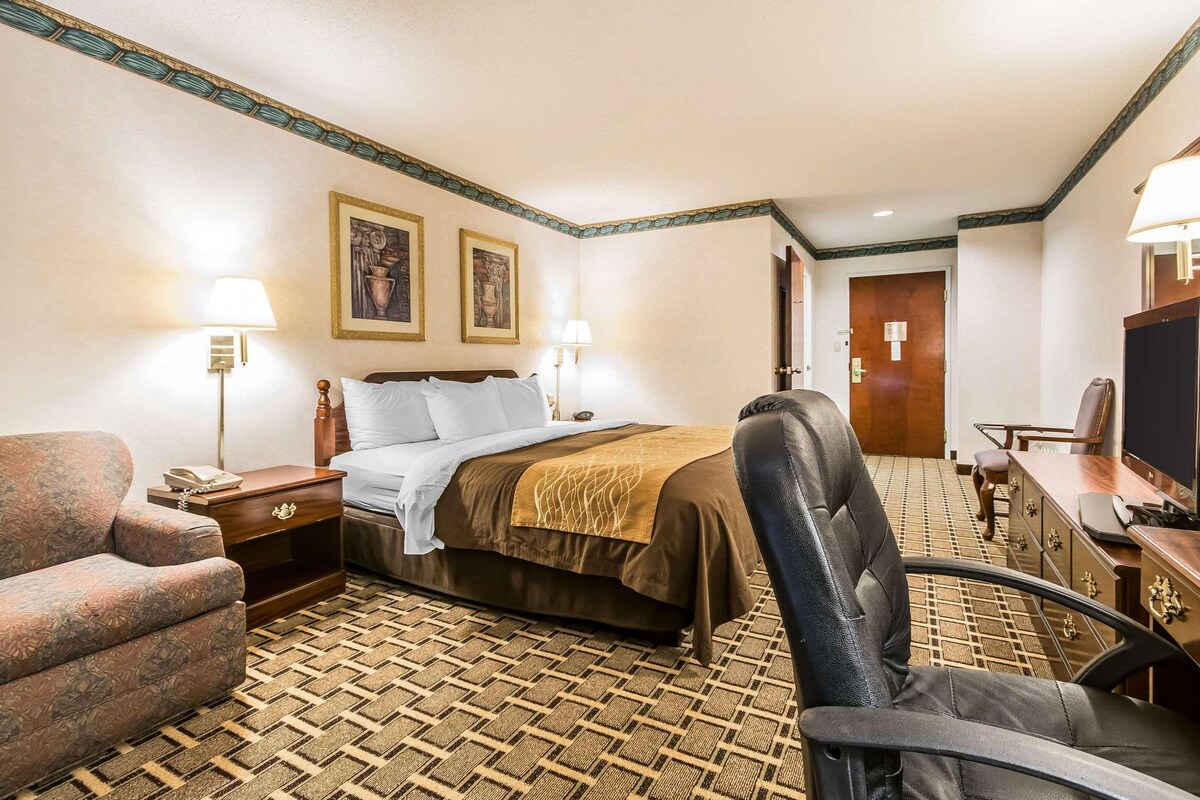 Una habitación de hotel con cama, escritorio, silla y televisor.