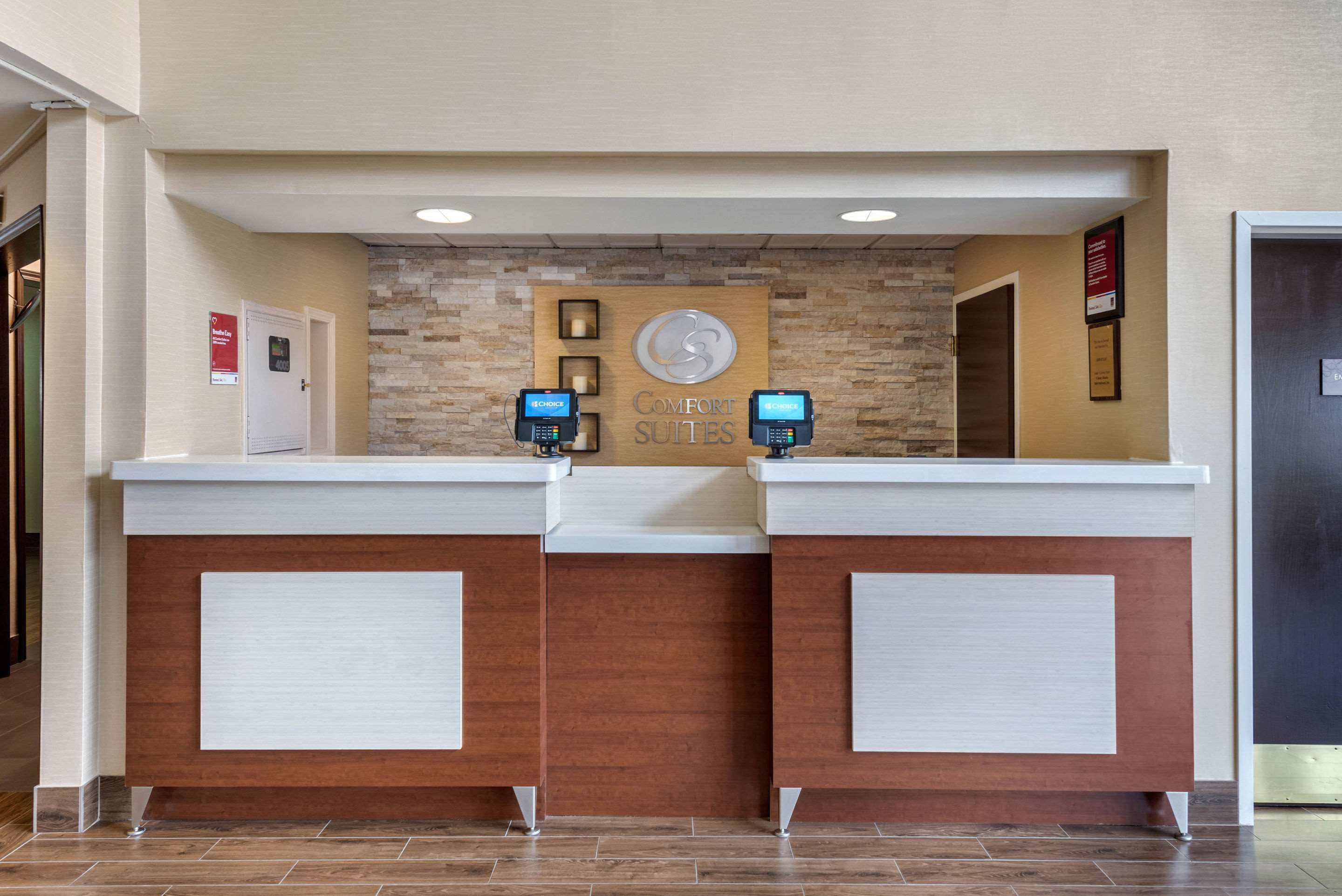 A reception desk with a clock, two ATMs, and a sign that reads "COMFORT SUITES".