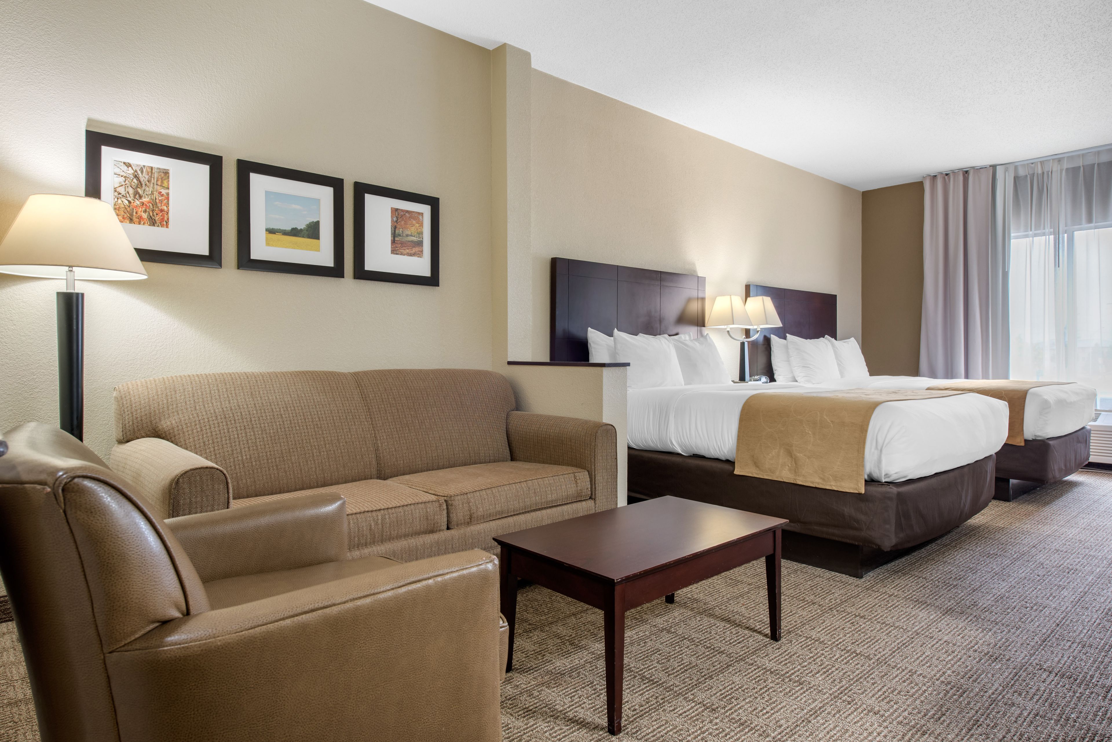A hotel room with a bed, a sofa, a coffee table, and a lamp.