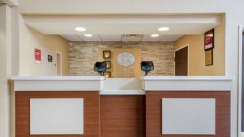 A reception desk with a wooden finish and a clock above it.