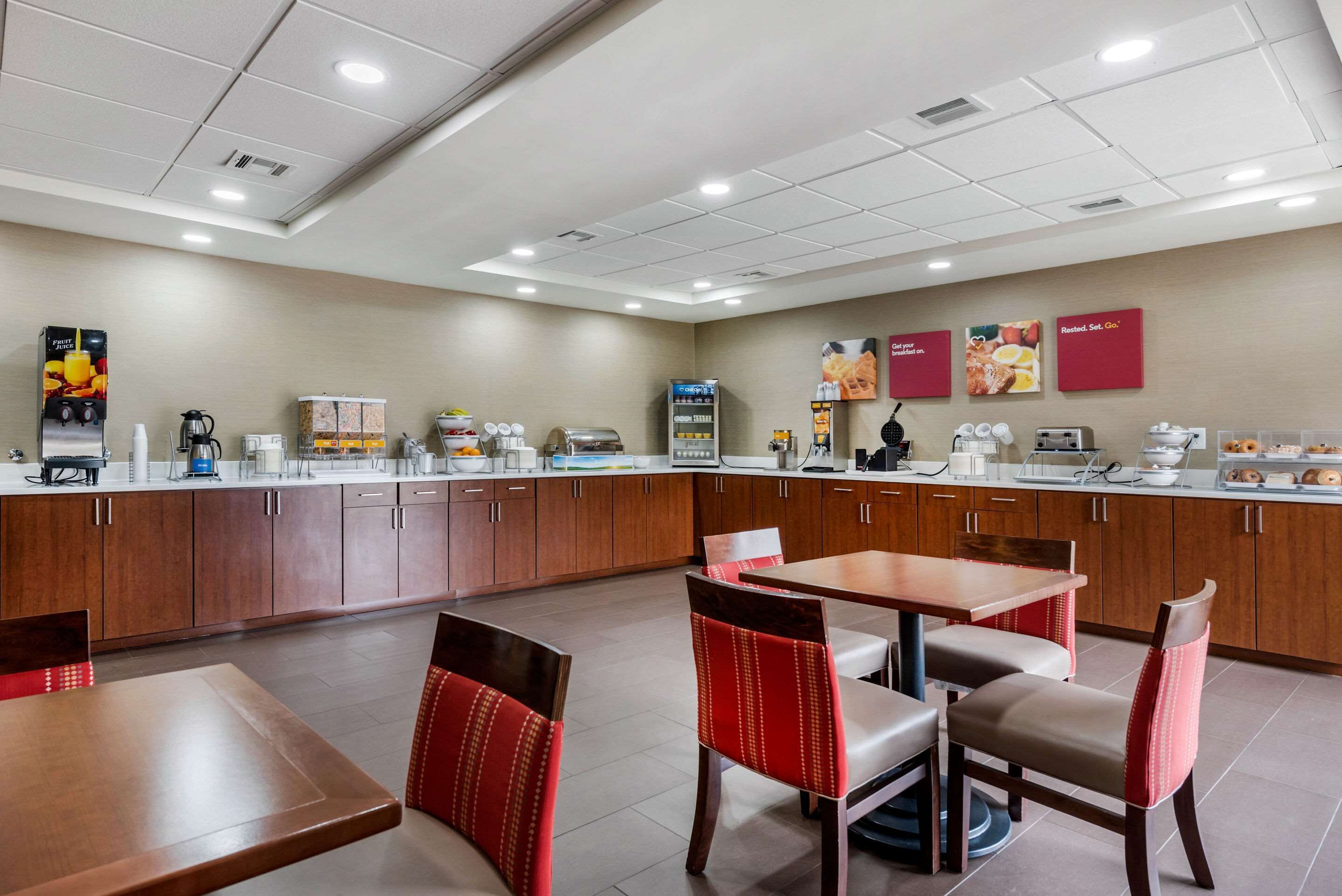 A modern breakfast area with a counter, seating, and various food and beverage stations.