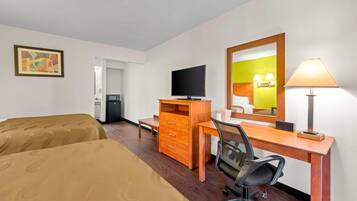 A hotel room with two beds, a desk with a chair, a television, a dresser, and a mirror.