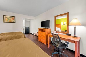 A hotel room with two beds, a desk with a chair, a television, a dresser, and a mirror. - Quality Inn Henderson I-85 (Henderson)