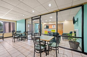 Un espacio interior moderno con divisiones de vidrio, mesas y sillas de madera, con un letrero que dice 'Quality by choice hotel'.