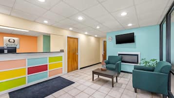 A reception area with a colorful counter, a reception desk, a television, and seating with a fireplace.