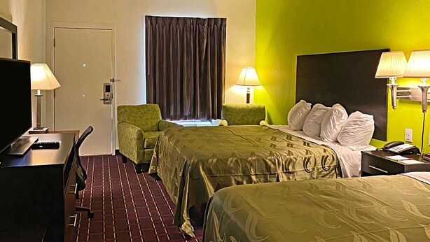 A hotel room with two beds, a desk, a chair, a TV, and two lamps. - Quality Inn Henderson I-85 (Henderson)