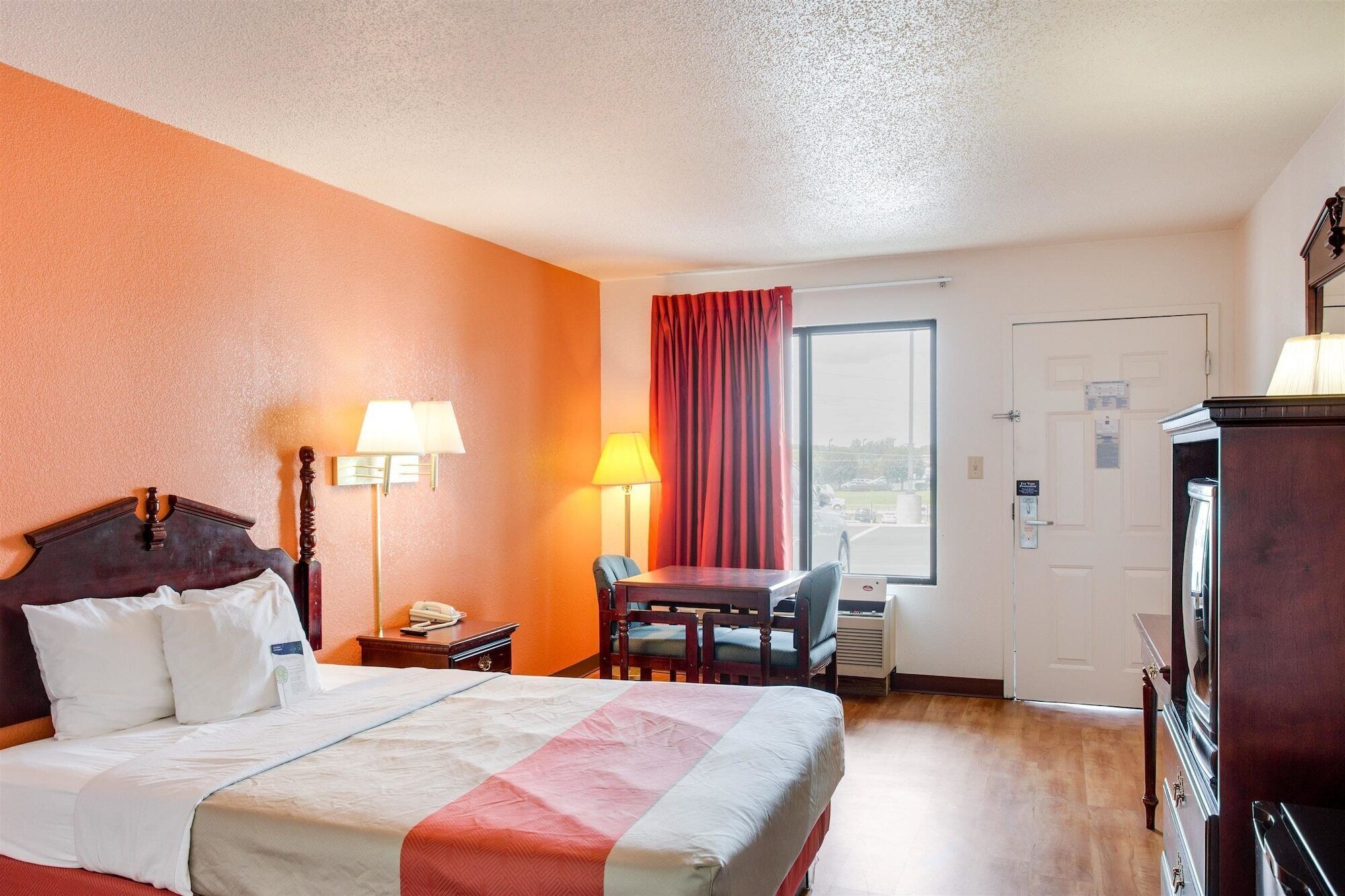 Una habitación de hotel con cama, escritorio, silla y vistas al exterior.