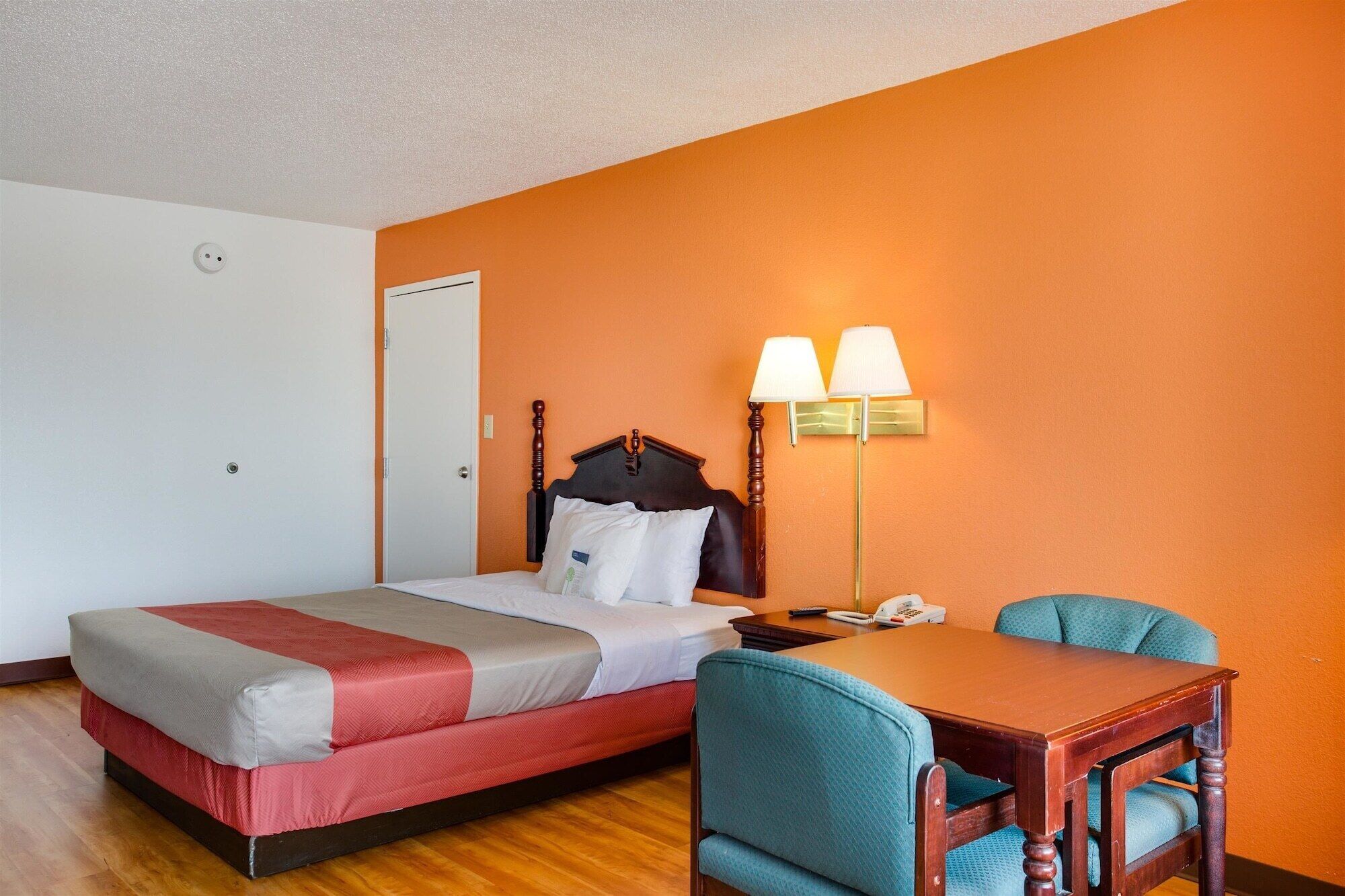 A hotel room with a bed, a desk, and two chairs.