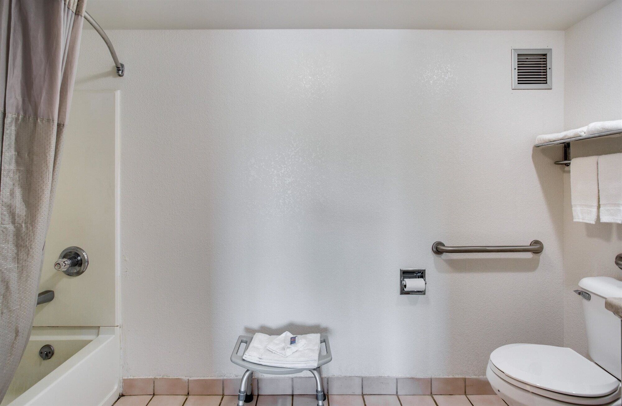 A bathroom with a shower, toilet, and a small table with towels.