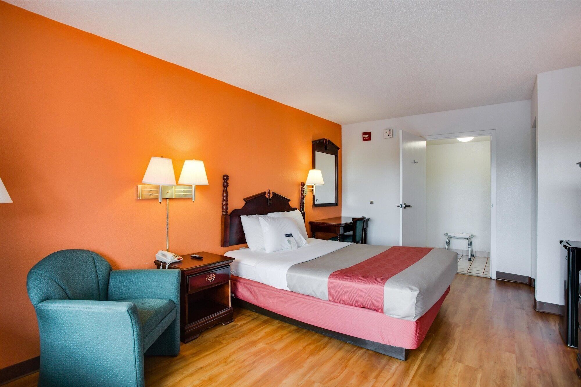 Une chambre d’hôtel comprenant un lit, une table de chevet, une chaise, un bureau et un miroir.