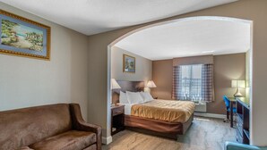 Quarto de hotel com cama, escrivaninha, cadeira e sofá.