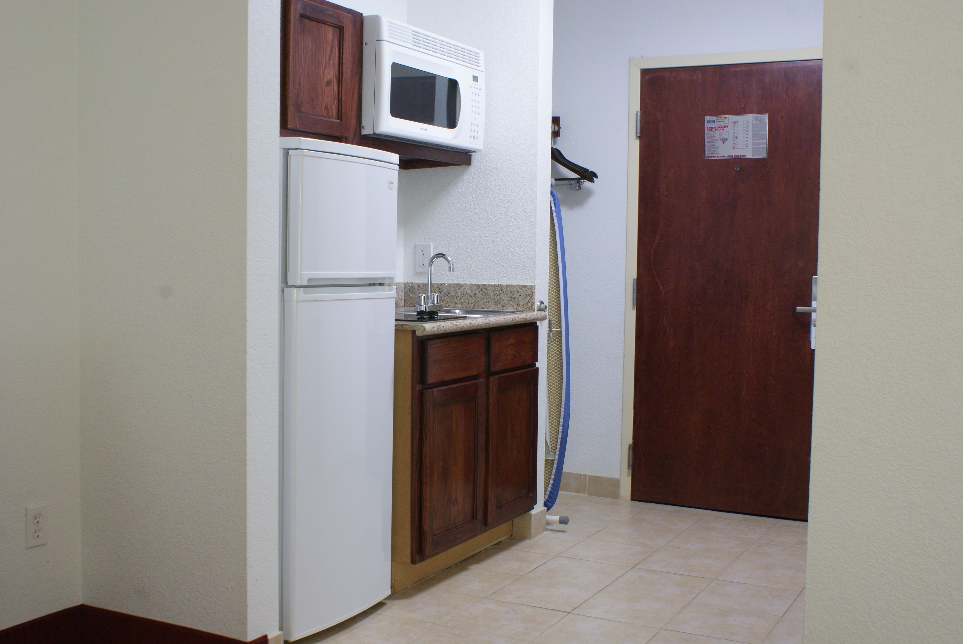 A compact kitchen with a white refrigerator, a microwave, and a sink.