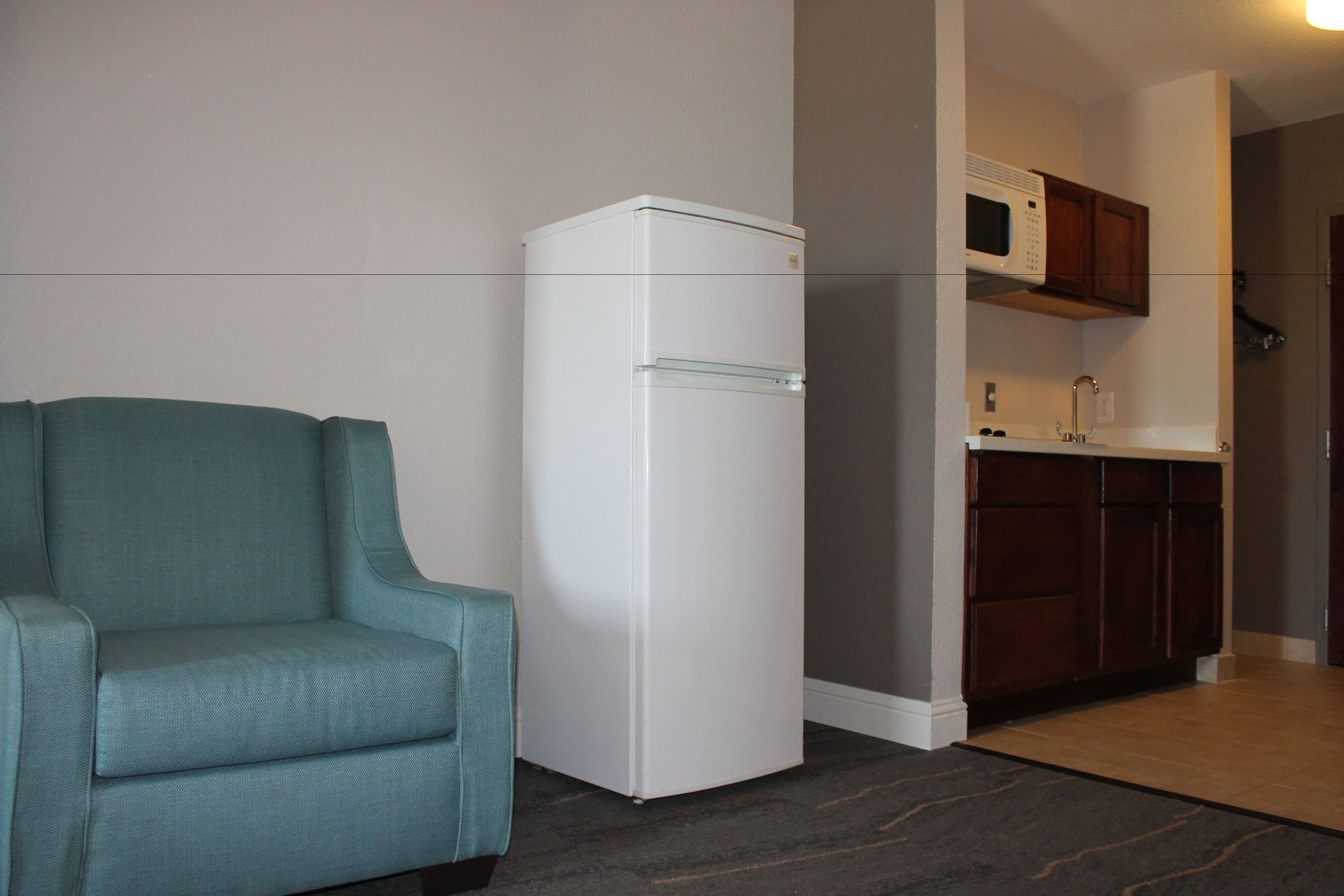 Una cocina compacta con refrigerador, microondas y armarios de madera.