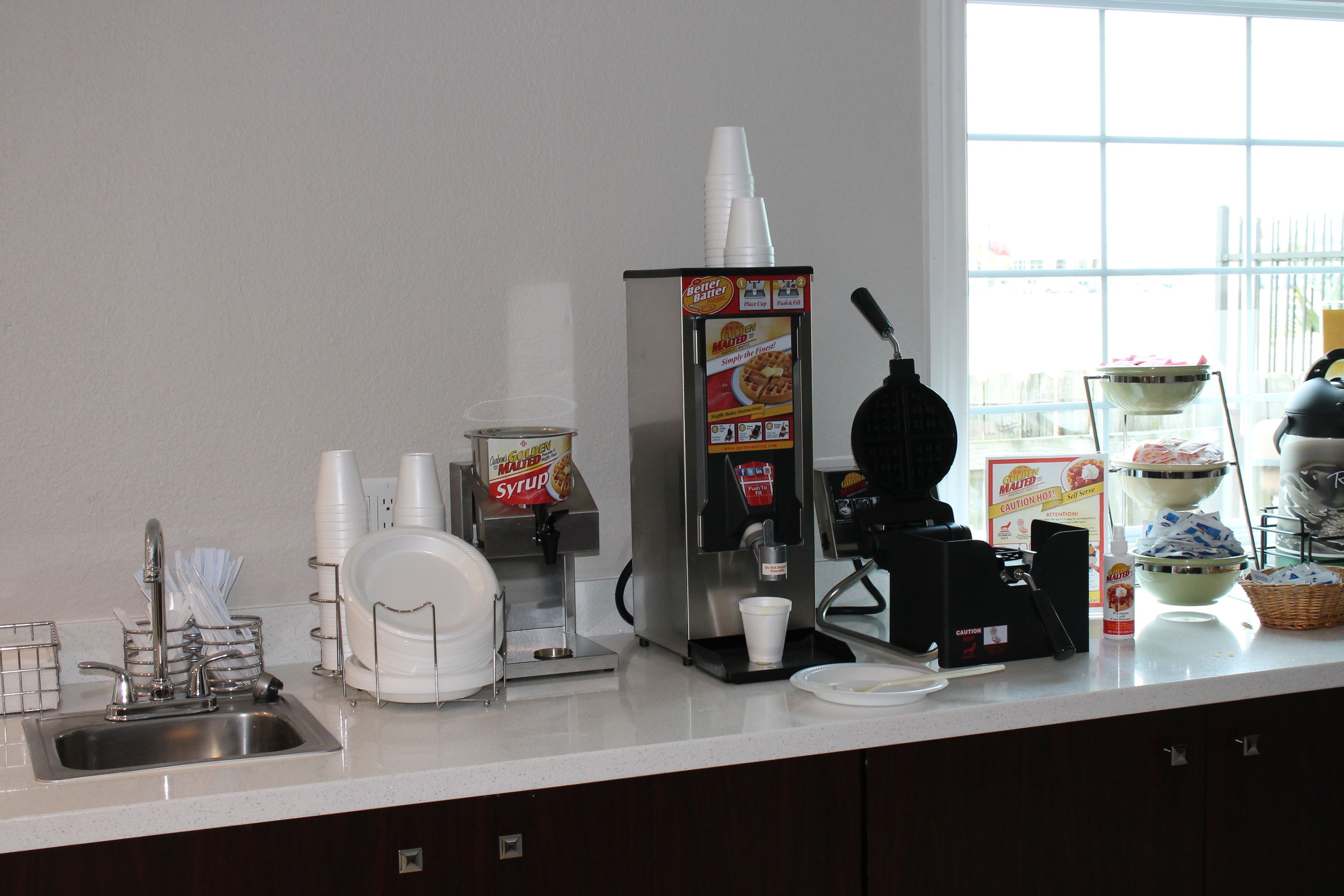 A kitchen area with a coffee machine, a beverage dispenser, and various kitchen utensils.