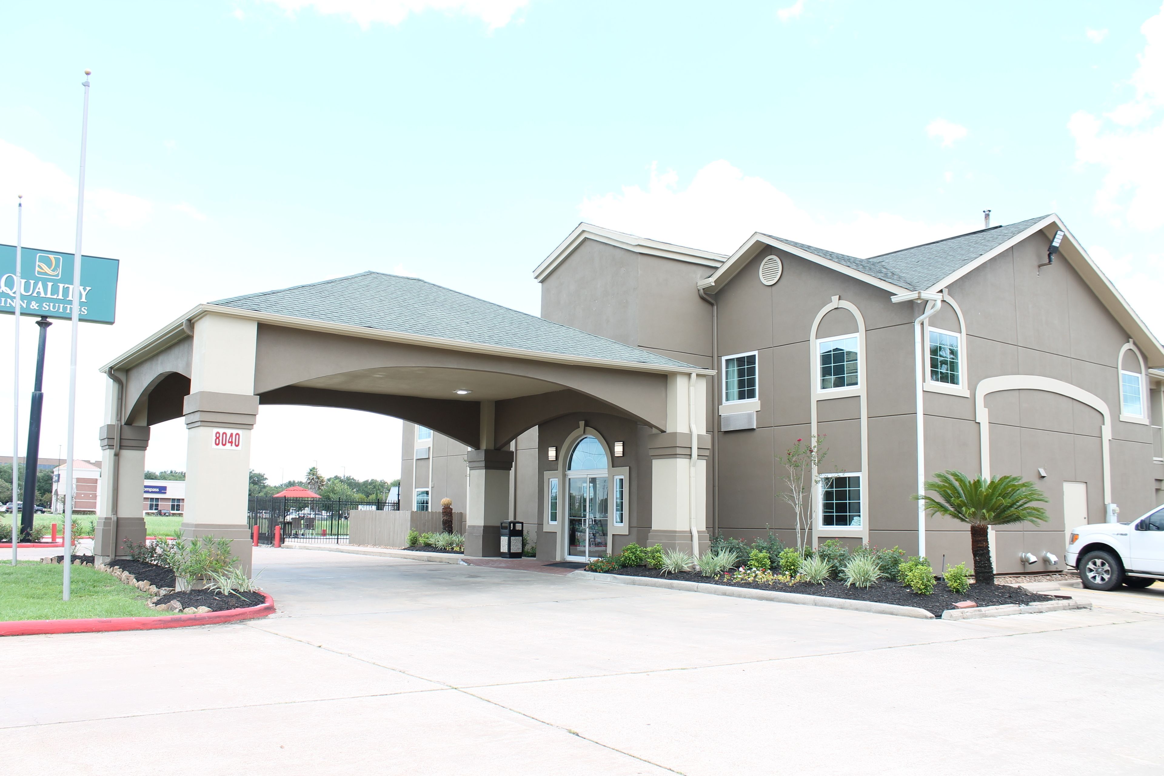 A hotel entrance with a covered walkway, a signboard, and a parking area.