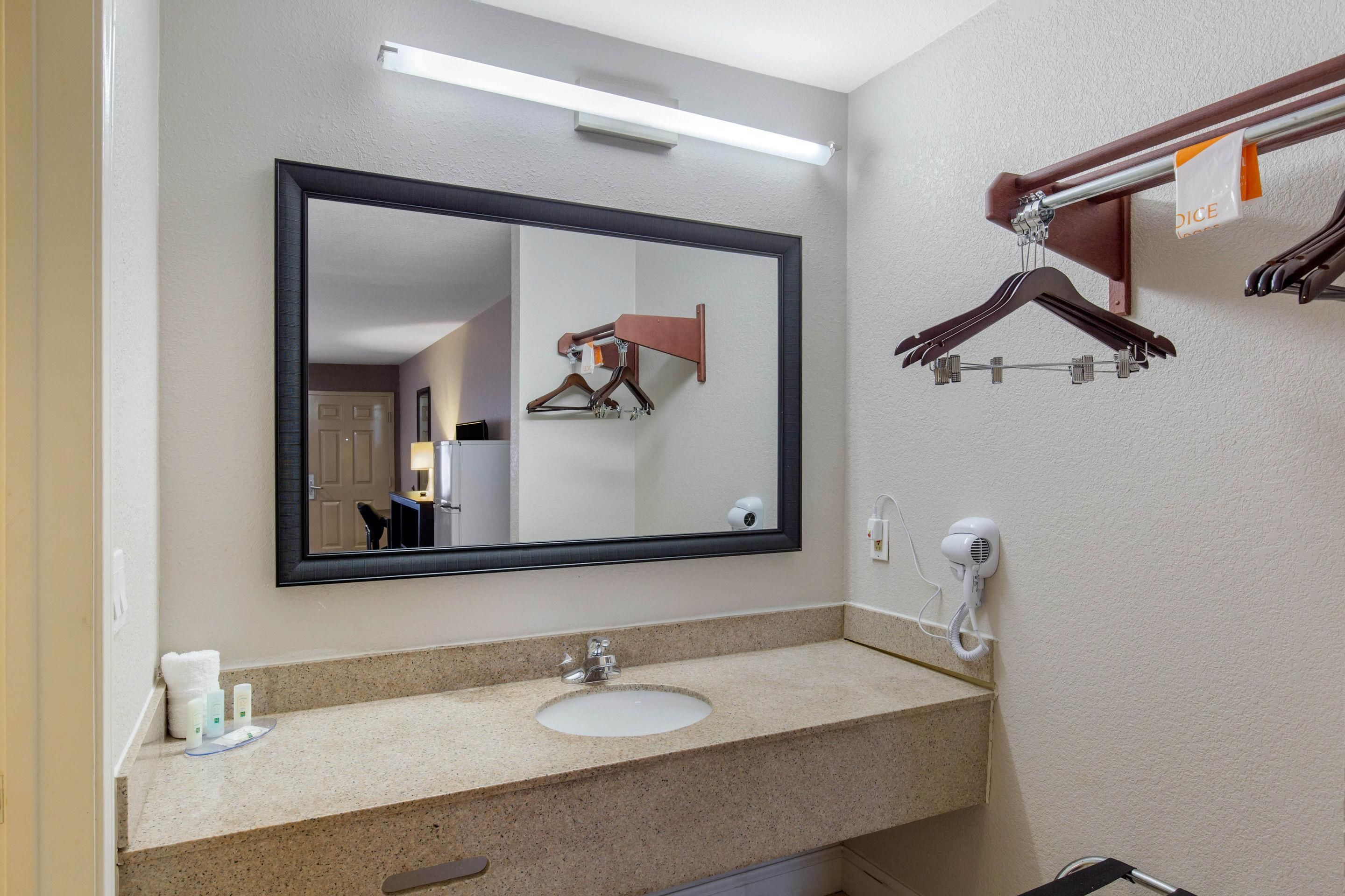 Un baño de hotel con un espejo grande, un lavamanos, un dispensador de toallas y un secador de pelo.