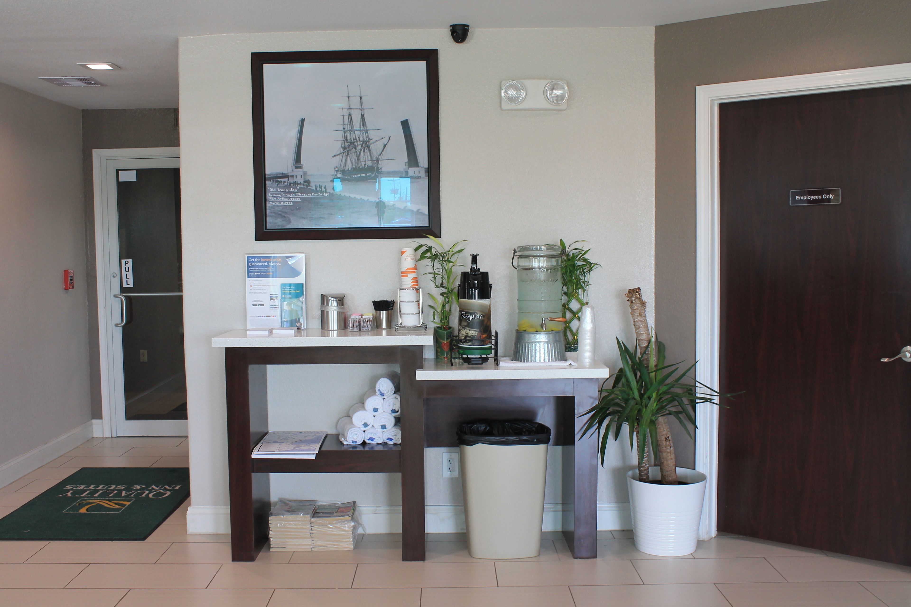 A reception area with a desk, a framed picture, a water dispenser, and a trash can.
