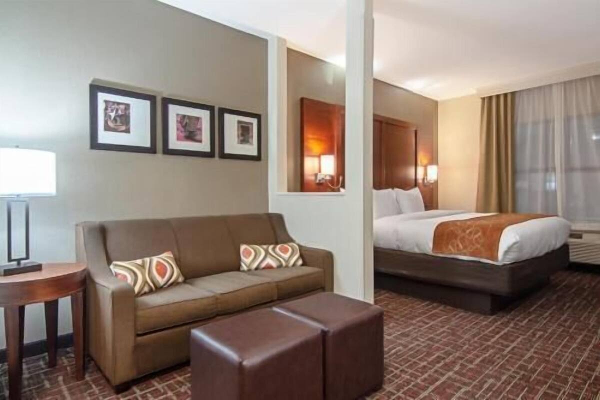 Una camera d'albergo con un divano, un letto, un tavolino e uno specchio.