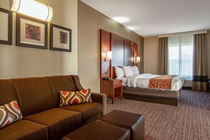 A hotel room with a sofa, a bed, a desk, and a window with curtains. - Comfort Suites NW Dallas Near Love Field (Dallas)
