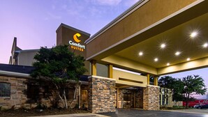 A Comfort Suites hotel exterior with a stone facade, large windows, and a covered entrance area. - Comfort Suites NW Dallas Near Love Field (Dallas)
