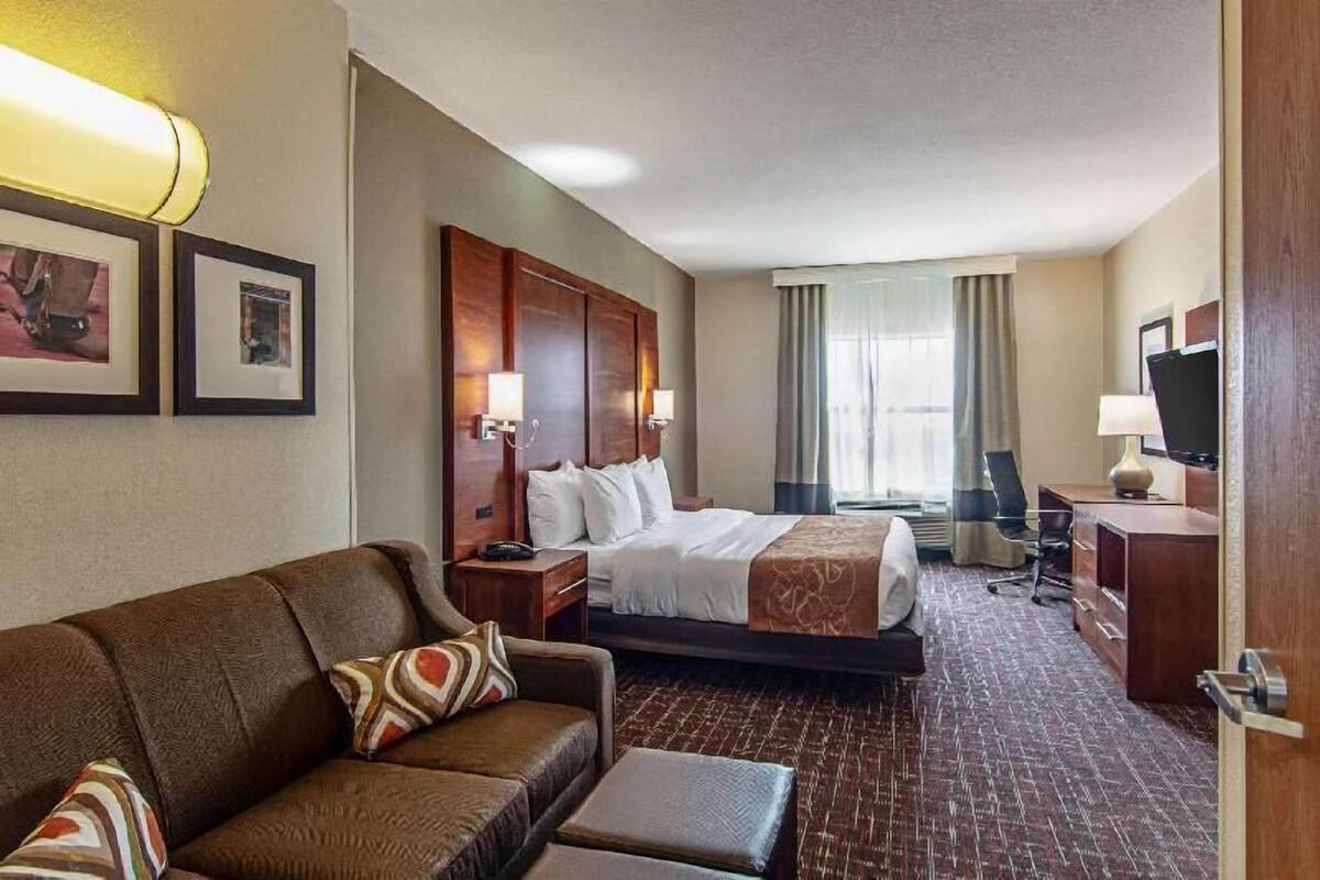 Una camera d'albergo con un letto, un divano, una scrivania e una televisione.