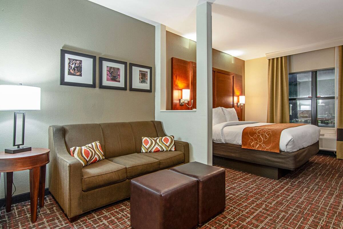Una camera d'albergo con un divano, un letto, un tavolino e una tappezzeria decorata.