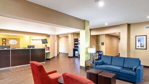 A hotel lobby with a reception desk, red and blue seating, and a television. - Comfort Suites NW Dallas Near Love Field (Dallas)