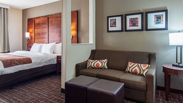 A hotel room with a bed, a sofa, a small table, and three framed pictures on the wall. - Comfort Suites NW Dallas Near Love Field (Dallas)