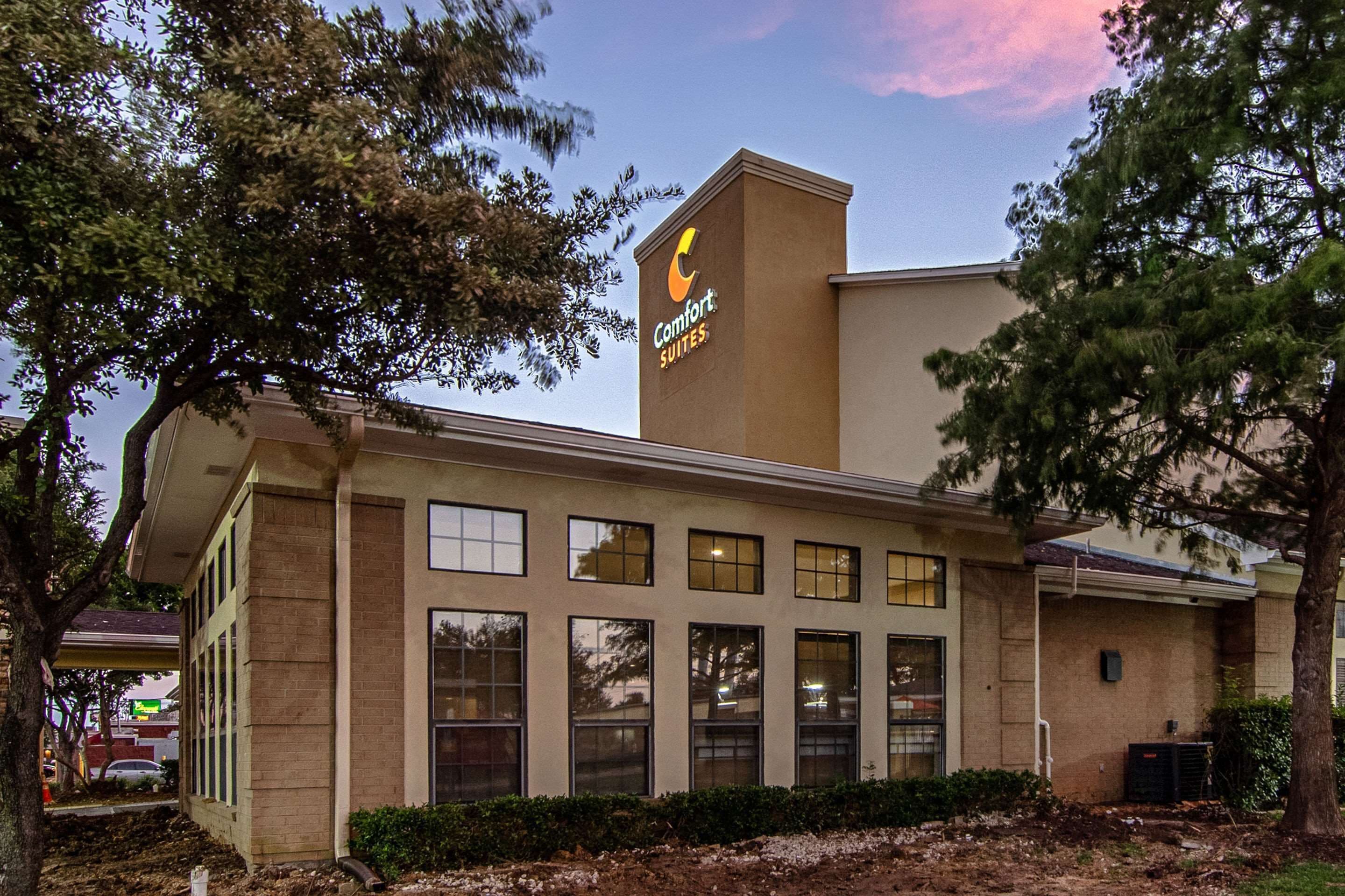 A Comfort Suites hotel building with a prominent sign, large windows, and a brick facade.