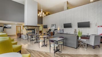 Um hall de hotel moderno com área de bar, sofás e uma lareira.
