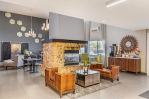 A modern lobby with a stone fireplace, comfortable seating, a bar area, and a large mirror on the wall. - Best Western Plus Wenatchee Downtown Hotel (Wenatchee)