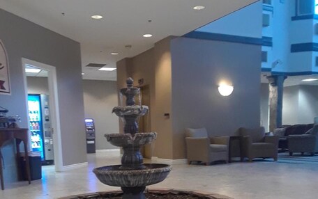 A lobby with a central fountain, seating area, and a vending machine.