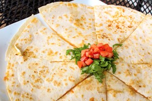 A plate of quesadillas with a garnish of diced tomatoes and lettuce. - The Comstock Inn and Conference Center (Owosso)