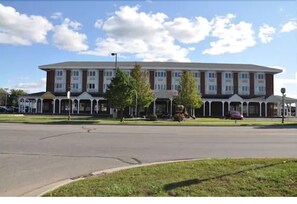 A large, multi-story building with a symmetrical facade, featuring a central entrance with a covered porch.