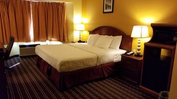 Een hotelkamer met een groot bed, twee bedlampen, een bureau met telefoon, een stoel en een schilderij aan de muur.