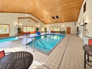 Una piscina interior con varias zonas de estar y techo de madera.