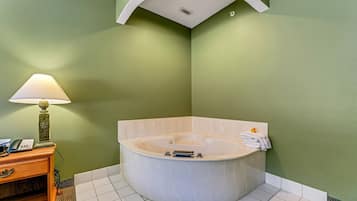 Un baño con una bañera independiente, un tocador con lámpara y un teléfono.