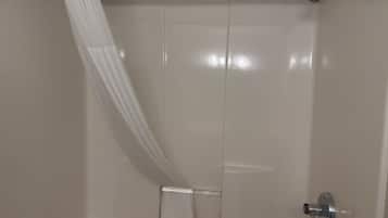 A shower with a white curtain and a handheld showerhead.