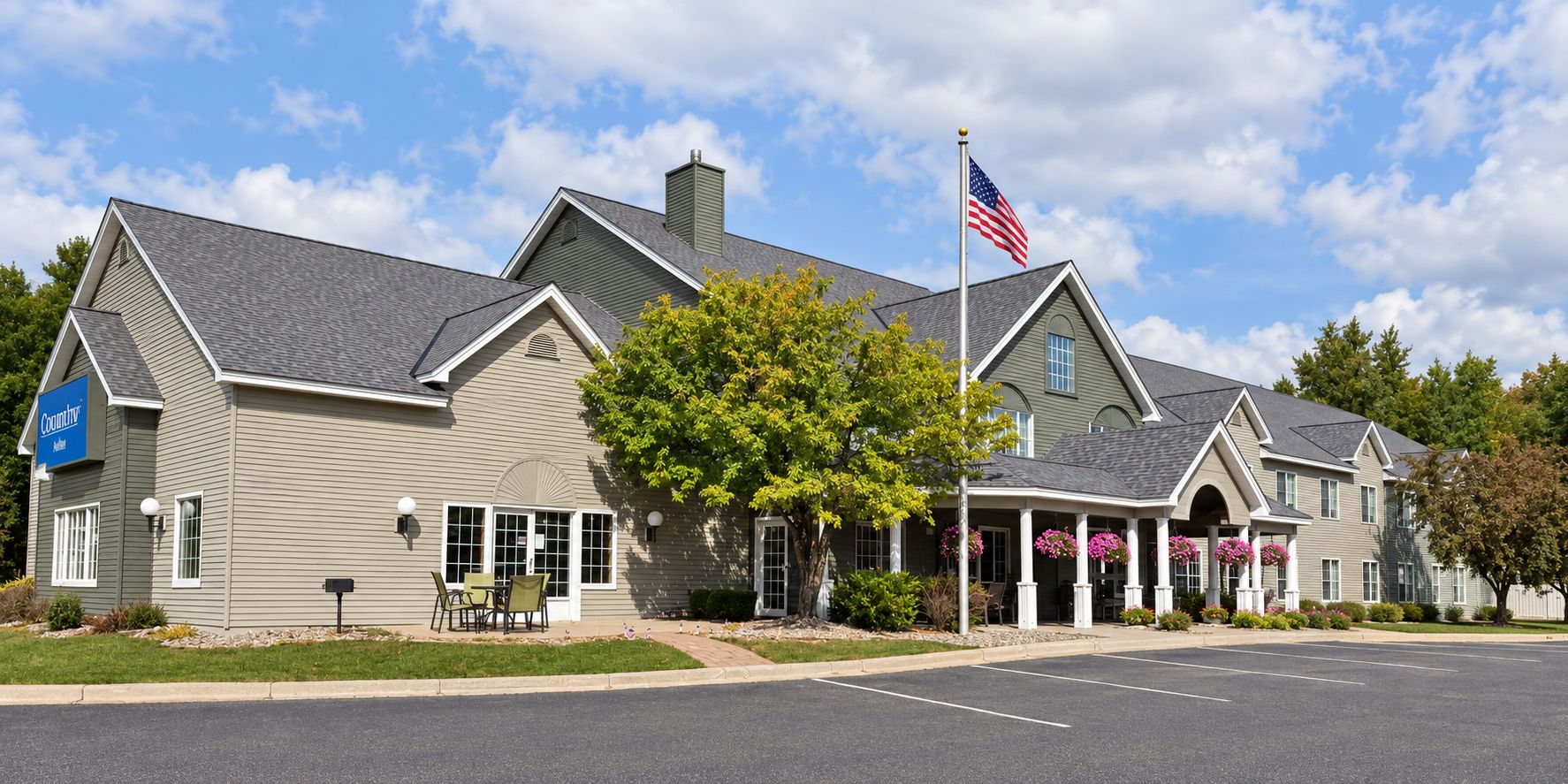 A two-story building with a flagpole, a signboard, and a parking lot.