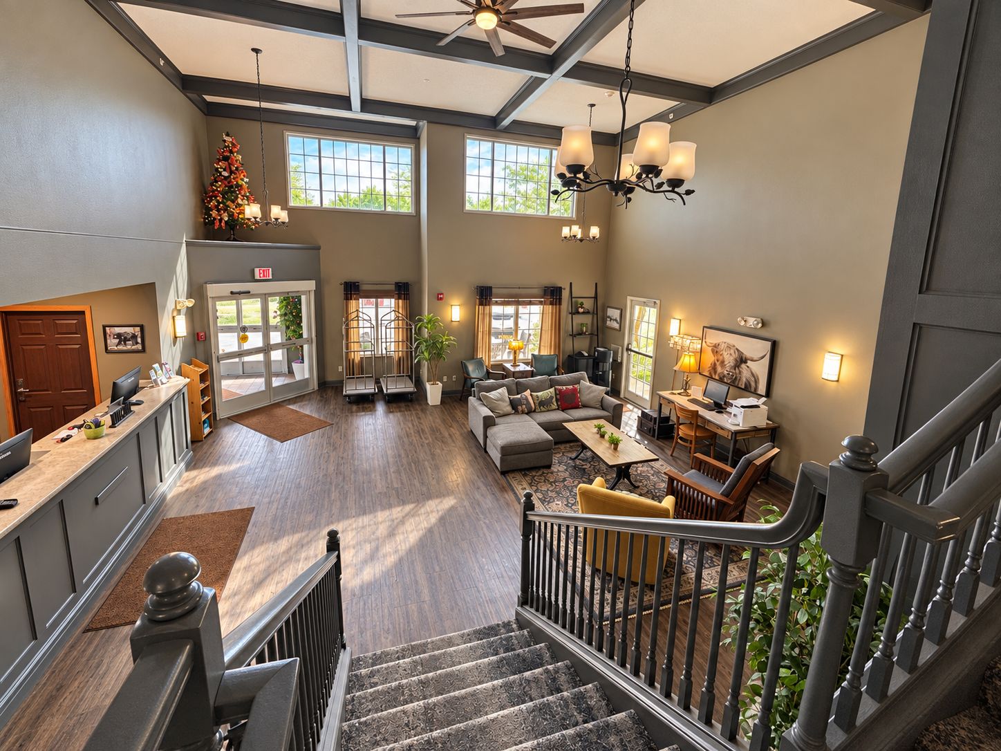 A spacious hotel lobby with a staircase, seating area, and a reception desk.