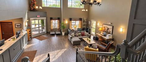 A spacious hotel lobby with a staircase, seating area, and a reception desk.