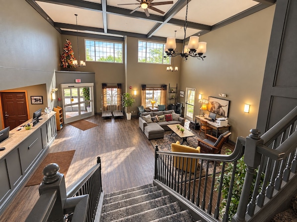 A spacious hotel lobby with a staircase, seating area, and a reception desk.
